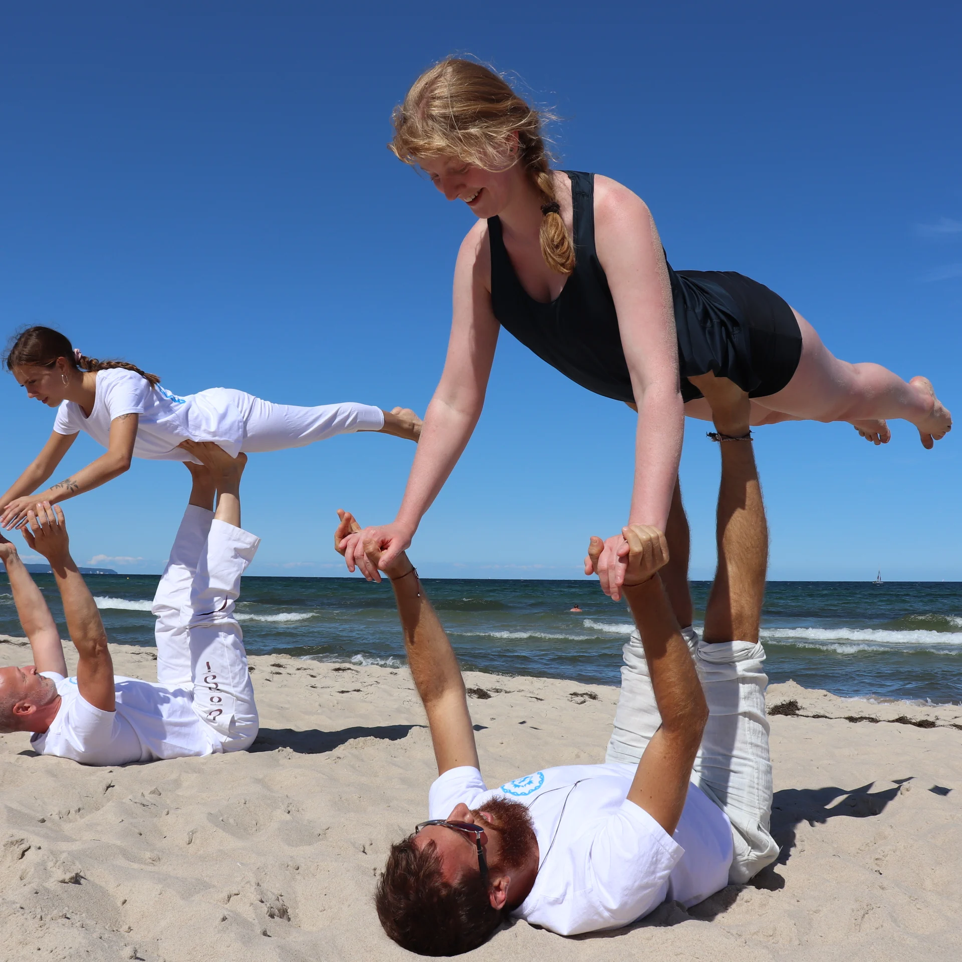 Partner-Yoga am Strand bei blauem Himmel