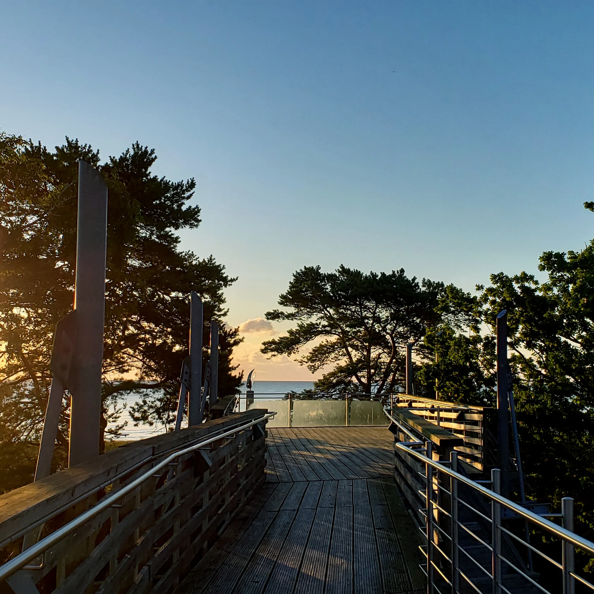 Holzterrasse mit Blick durch die Bäume zum Meer